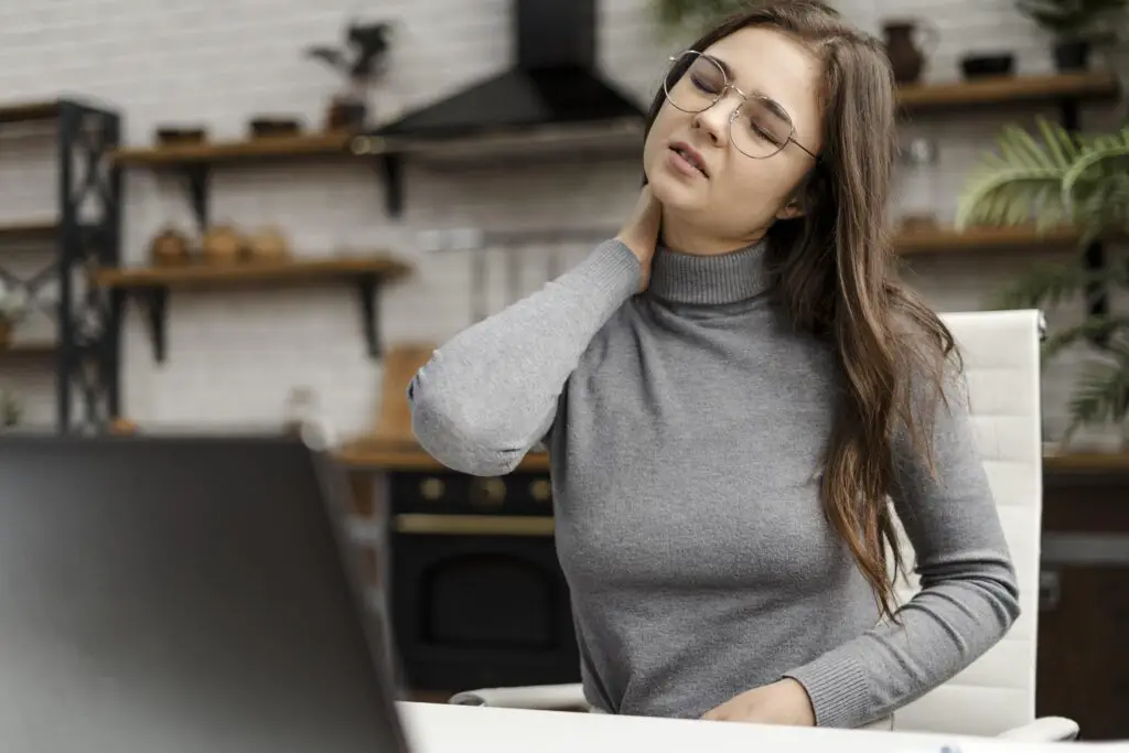 young woman having neckache while working from home