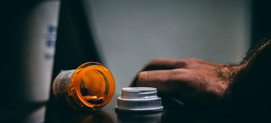 A man’s hand next to a prescription bottle