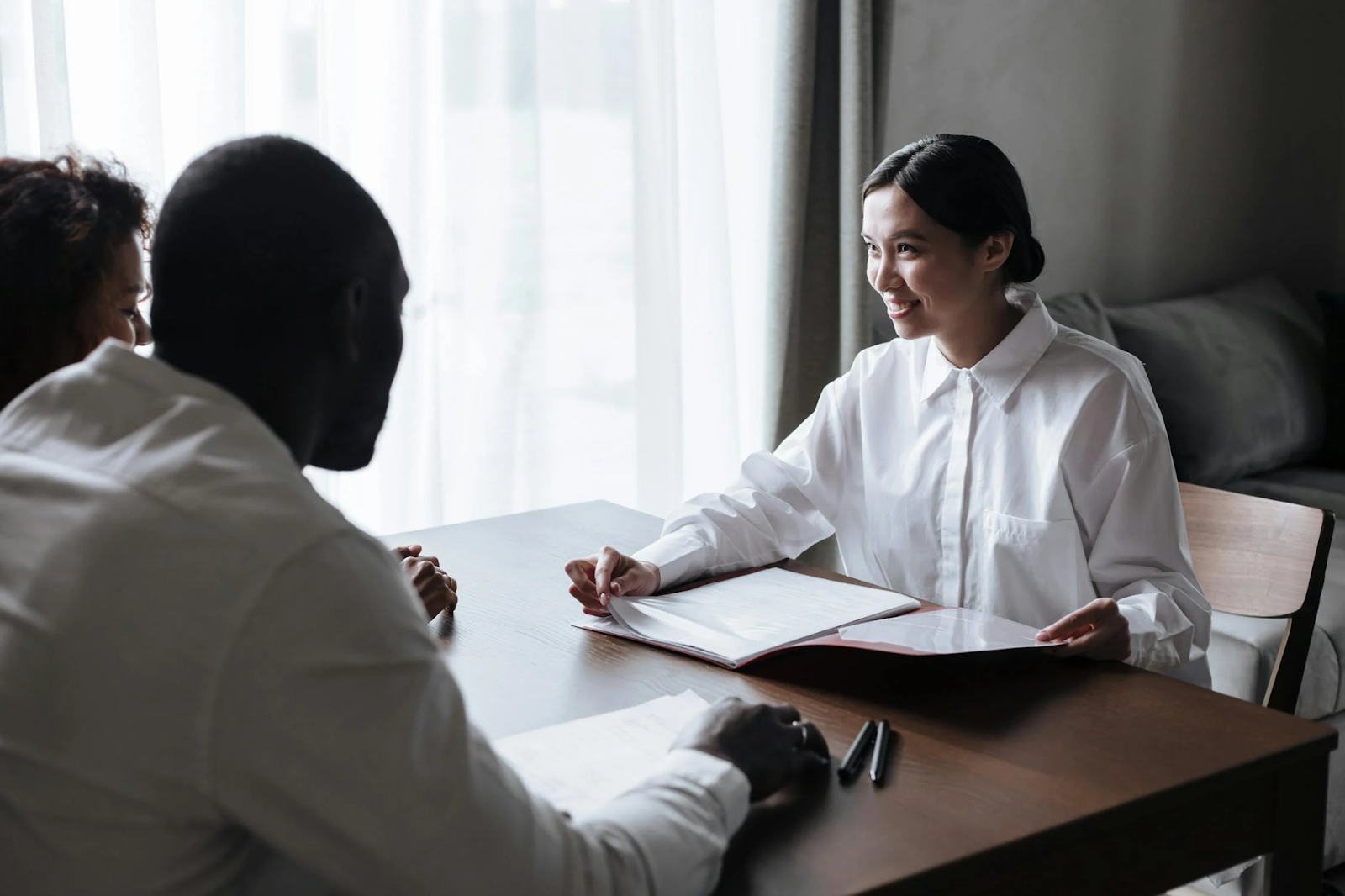 A woman in white long sleeves talking to a couple 