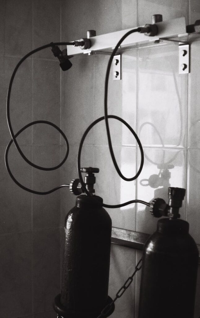 Monochrome photograph showing two oxygen cylinders in a hospital setting.