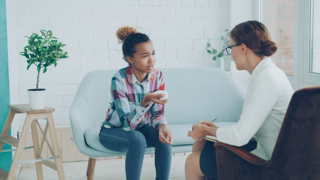 How Health Psychology Complements Traditional Counseling and Social Work Roles 3 Therapist talking to a young girl on couch.