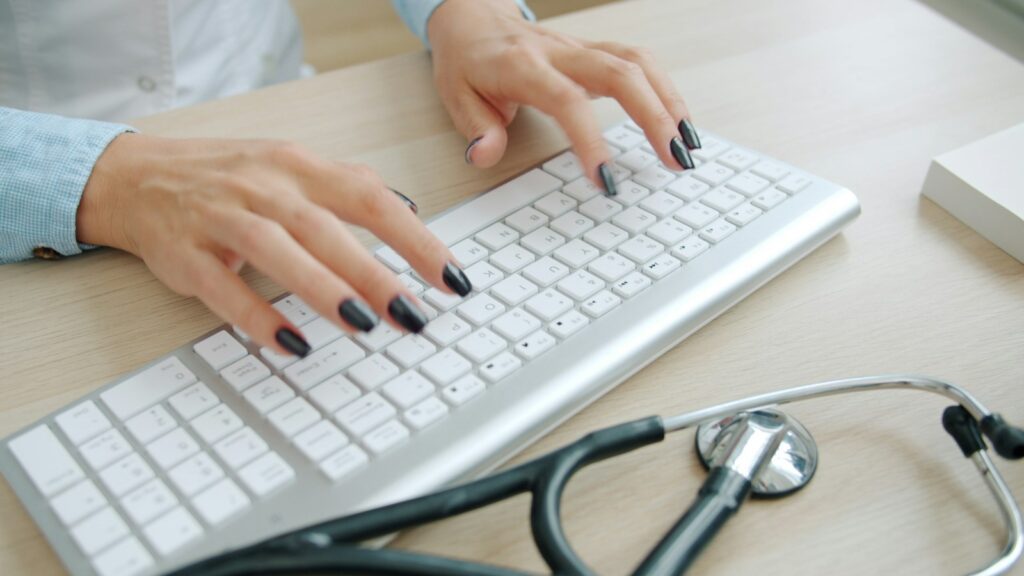What Should Mental Health Practices Prioritize When Choosing an EHR? 2 Doctor typing on keyboard with stethoscope nearby